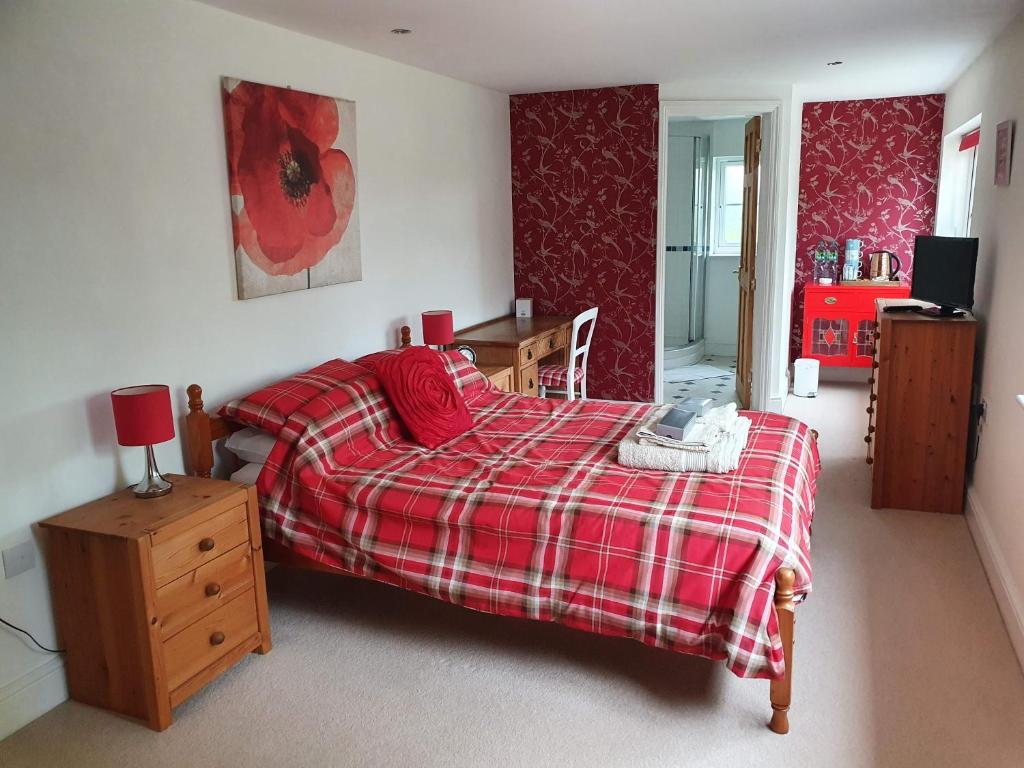 1 dormitorio con 1 cama con manta de cuadros roja en Everlong Farm, en Diss