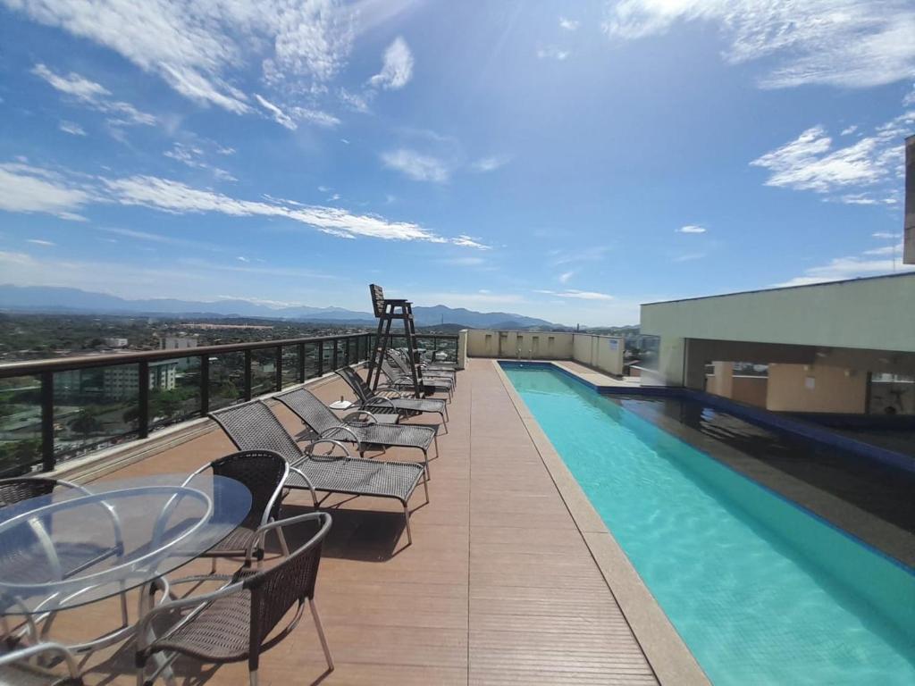 伊塔博拉伊的住宿－Flat moderno com piscina e academia，一个带椅子的阳台和一个位于大楼内的游泳池