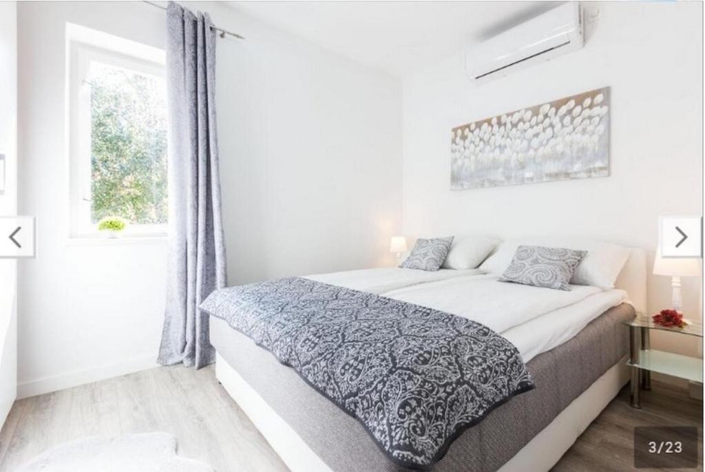 a white bedroom with a bed and a window at APARTMENT KAYA in Zadar