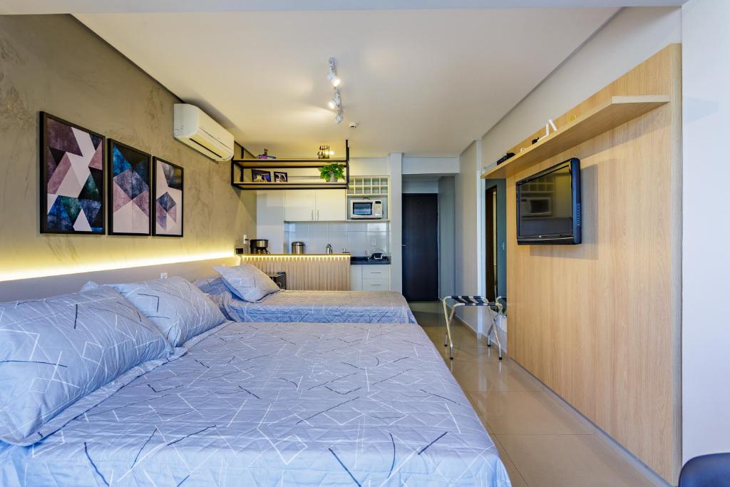 a bedroom with two beds and a tv on a wall at Apart Hotel Centro de Brasília - Garvey Park Hotel in Brasilia