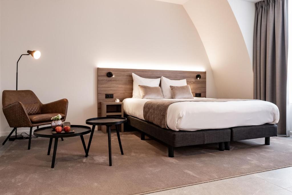 um quarto com uma cama, uma cadeira e uma mesa em Hotel Reynaert Bv em Hulst