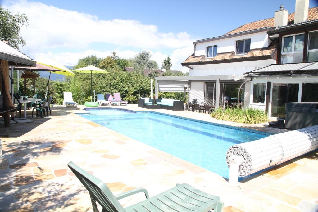 a swimming pool with chairs and a house at Super appart piscine proche Genève in Viry