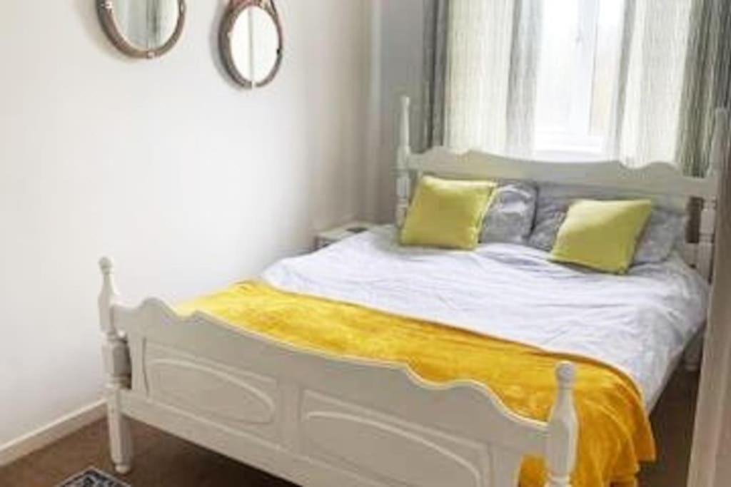 Cama blanca con almohadas amarillas y ventana en Home from Home sleeps seven en Hastings