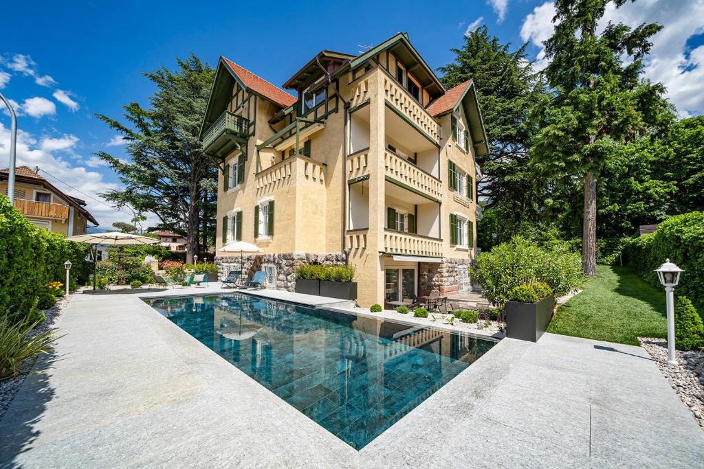 a large house with a swimming pool in front of it at Villa Tell rooms and suites in Merano