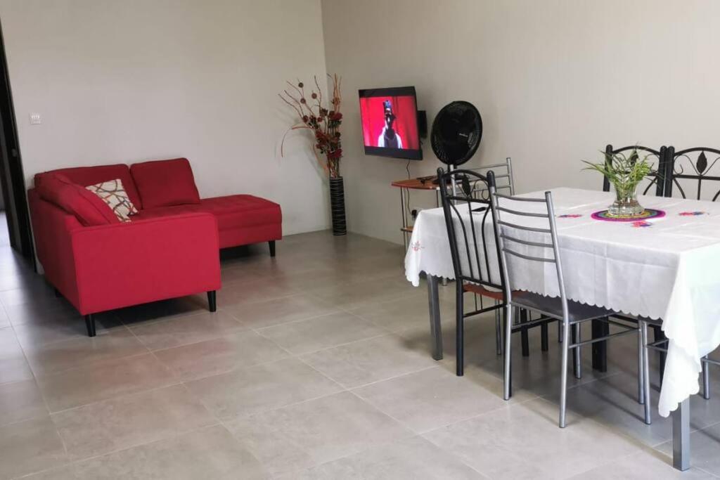 a living room with a table and a red chair at Cosy apartment on the 1st floor in Curepipe