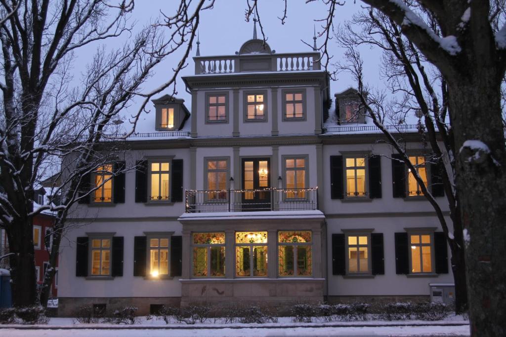 a large white house with its lights on at Hotel Villa Victoria in Coburg