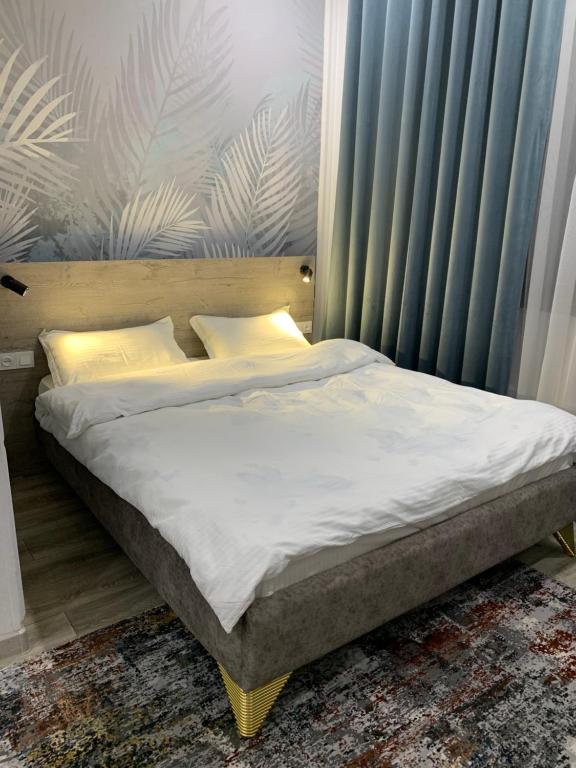 łóżko z białą pościelą i poduszkami w sypialni w obiekcie Magistral w mieście Biszkek