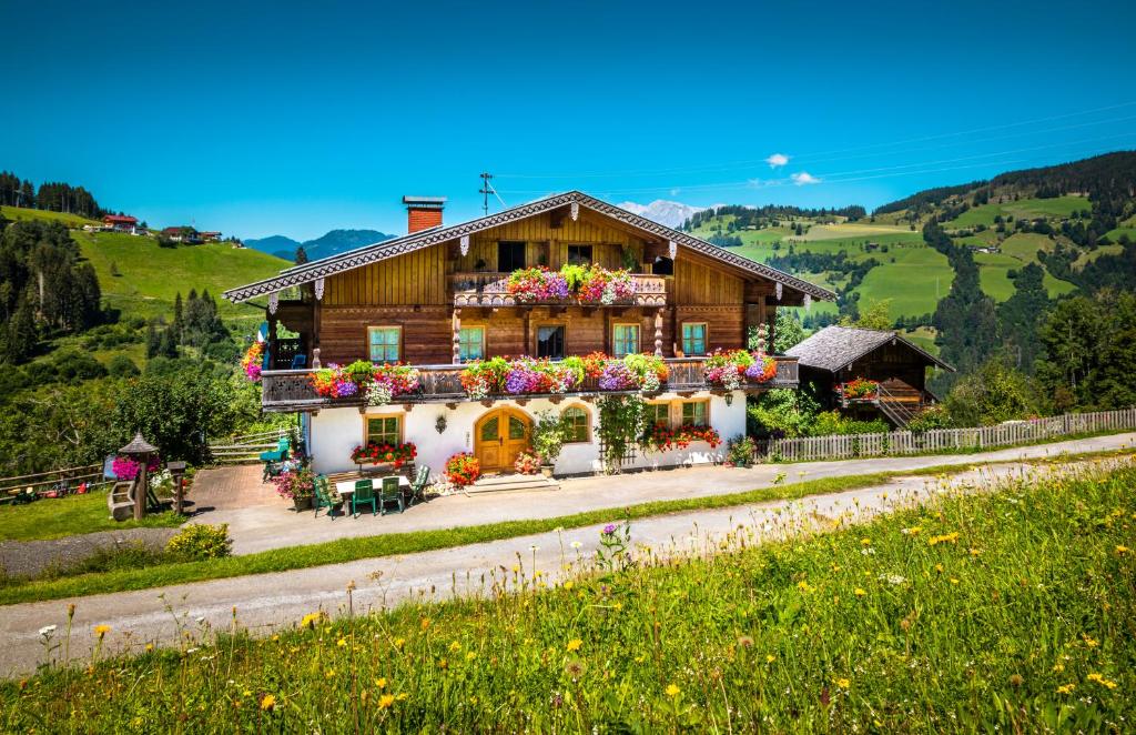 ein Haus auf einem Hügel mit Blumen darauf in der Unterkunft Hallmoosgut in St. Johann im Pongau