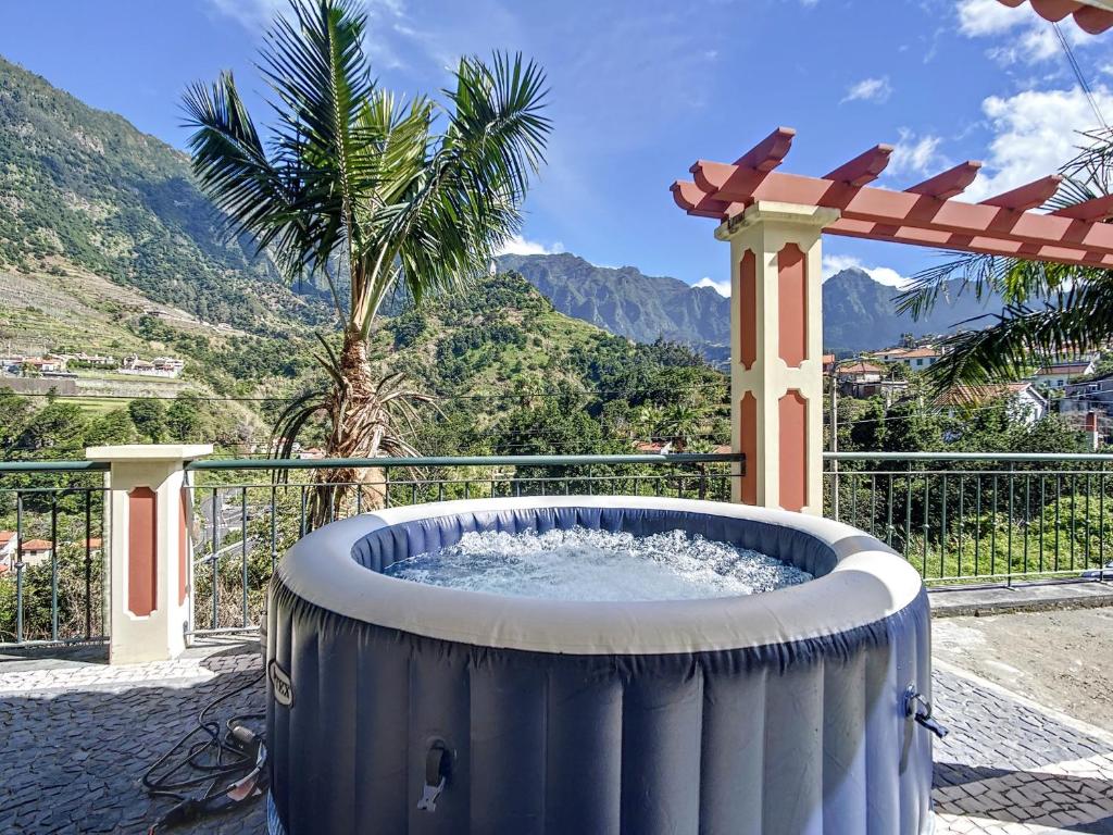 a hot tub on a patio with a palm tree at Mountain View Villa by Atlantic Holiday in São Vicente