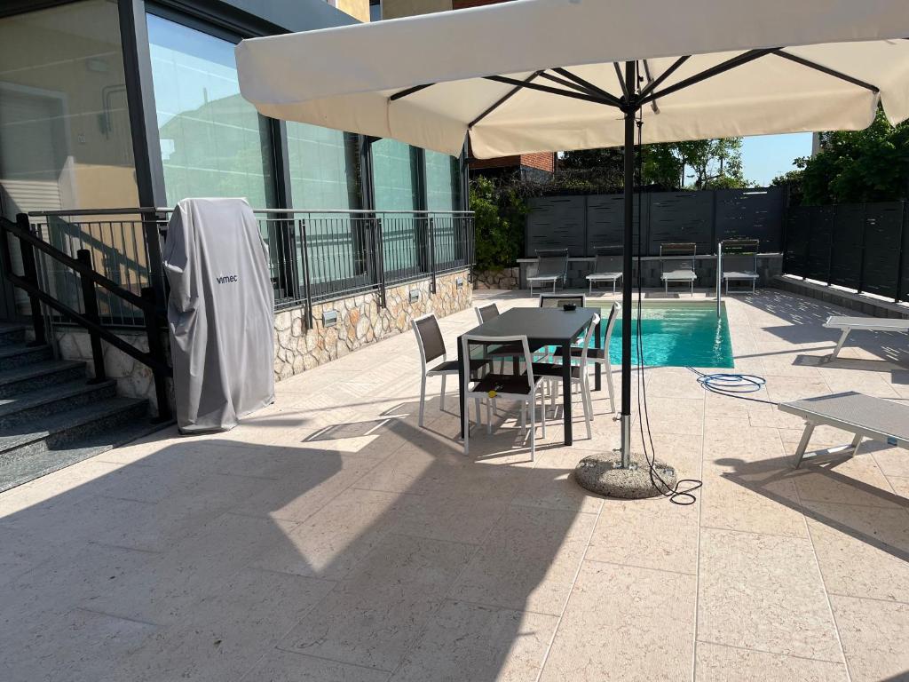 patio con tavolo e ombrellone accanto alla piscina di CASA DANZI a Peschiera del Garda