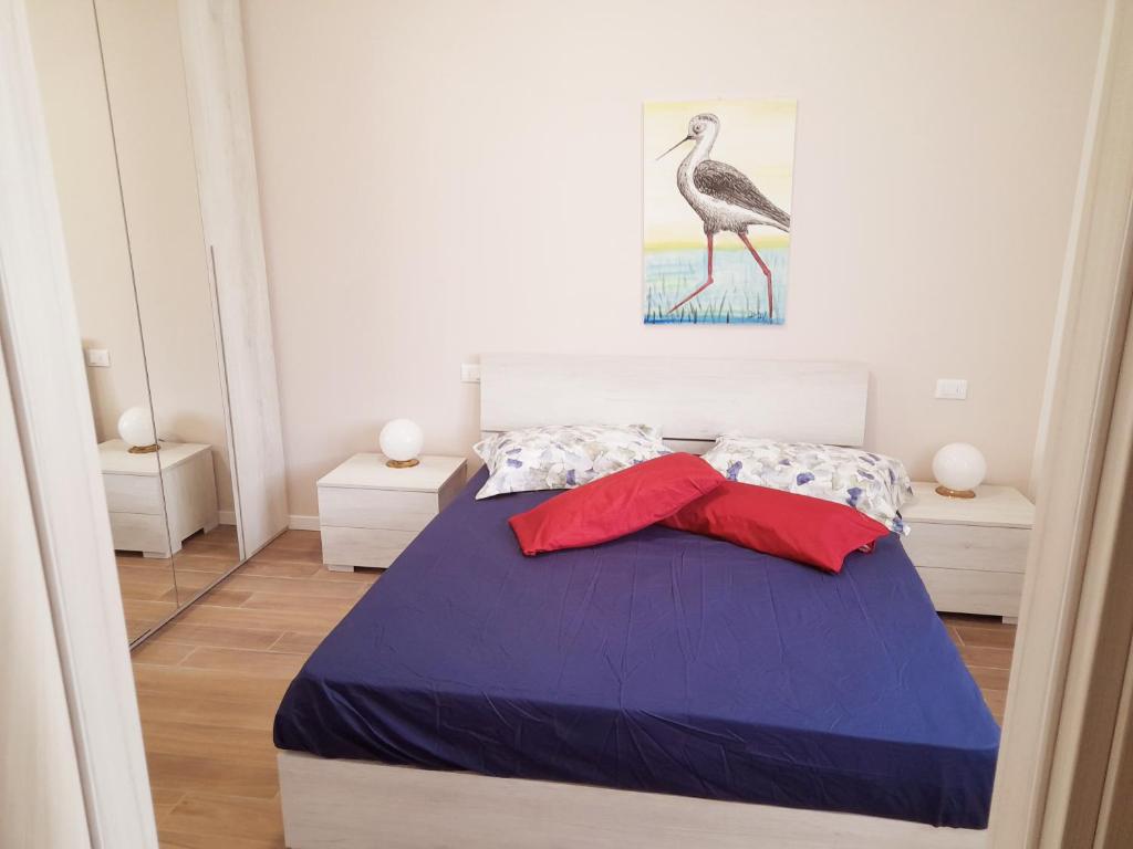 um quarto com uma grande cama azul com almofadas vermelhas em La Casera em Lido di Dante