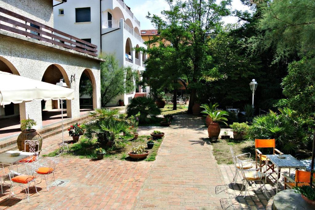 une cour avec des tables et des chaises et un bâtiment dans l'établissement Hotel Villa Furia, à Bellaria-Igea Marina