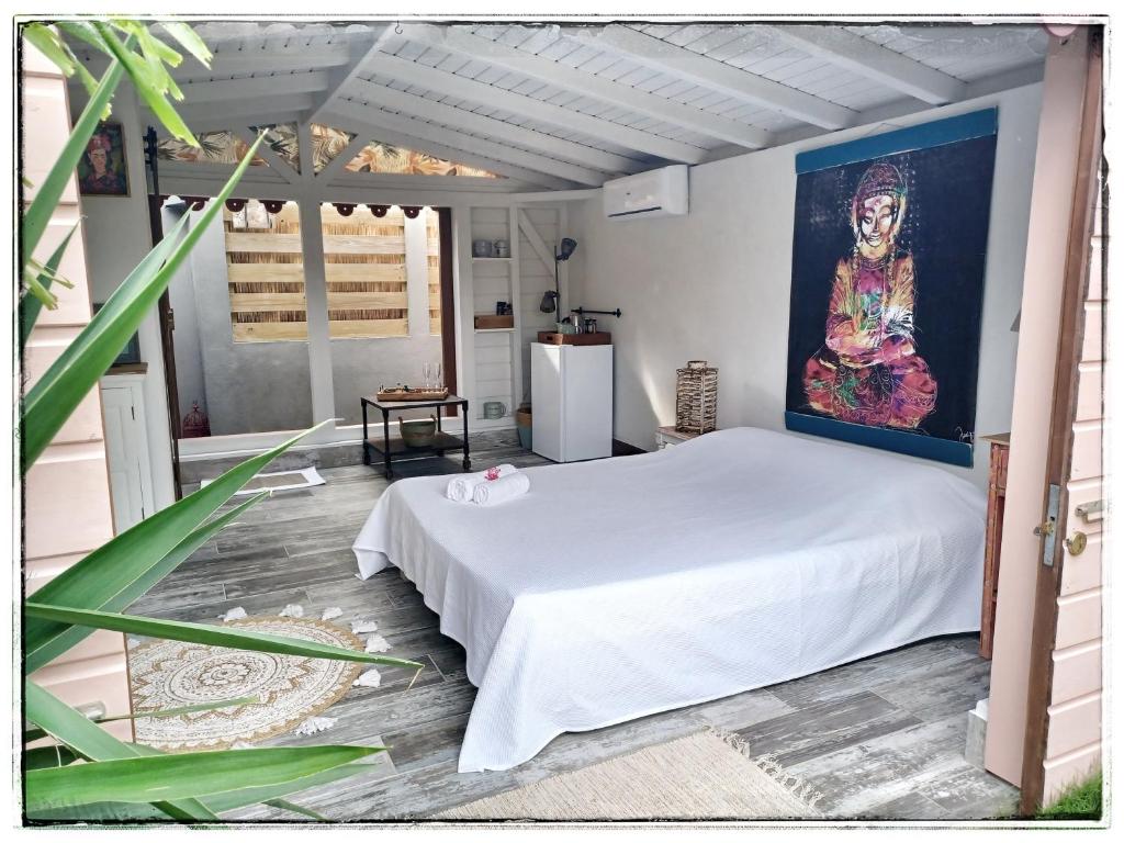 a bedroom with a bed and a painting on the wall at LA CABANE D'artiste in Cul de Sac