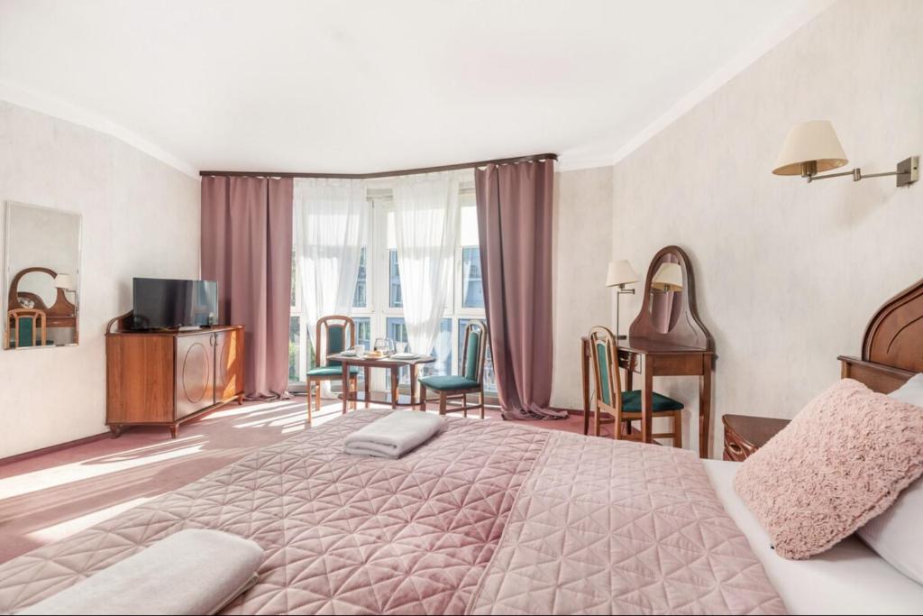 Un dormitorio con una cama grande y una mesa y sillas. en Apartamenty Baltic Sea 300 krokow od morza, en Kołobrzeg