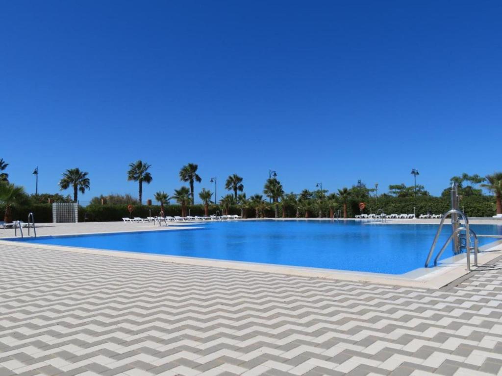 a swimming pool in a resort with palm trees at Ático de lujo - Luxury Penthouse in Huelva