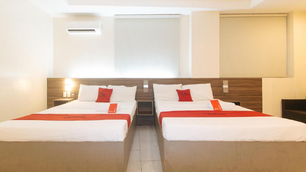 2 letti in camera con cuscini rossi di RedDoorz at V Plaza Hotel Manila a Manila