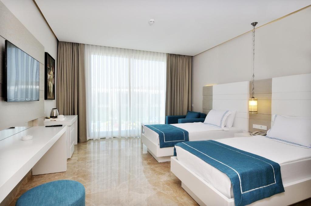 a hotel room with two beds and a bathroom at Lugga Boutique Hotel & Beach in Ortakent