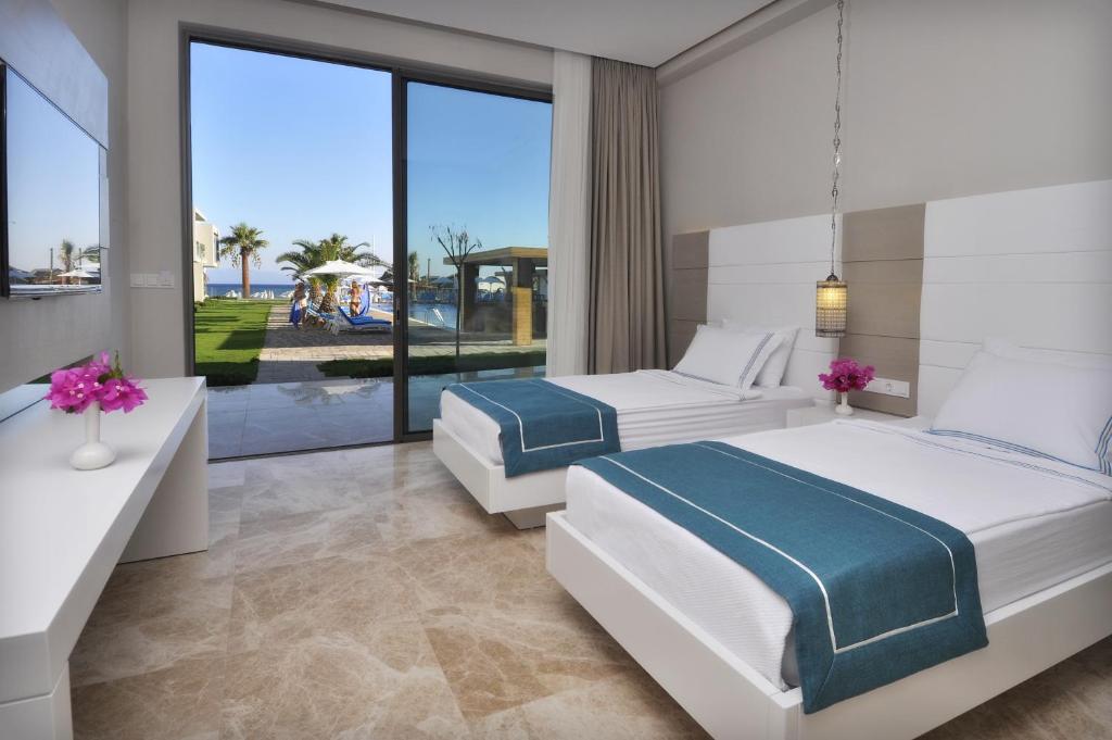 two beds in a bedroom with a view of the ocean at Luga Boutique Hotel & Beach in Ortakent