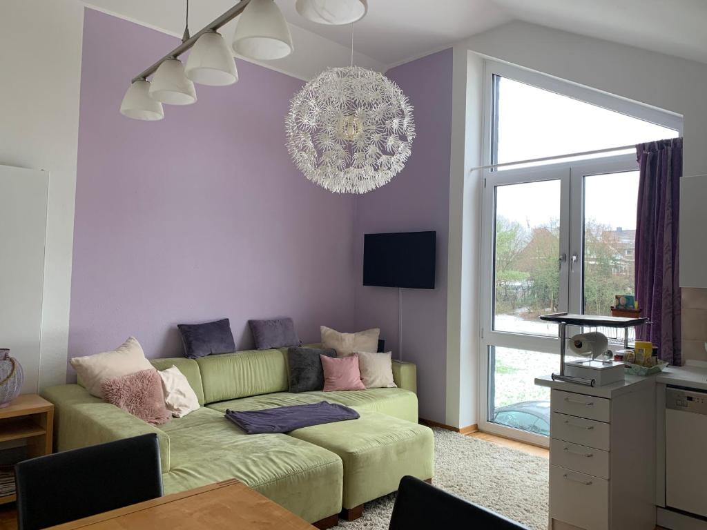 ein Wohnzimmer mit einem grünen Sofa und einem Kronleuchter in der Unterkunft Ruhige Wohnung an der Uni in Düsseldorf