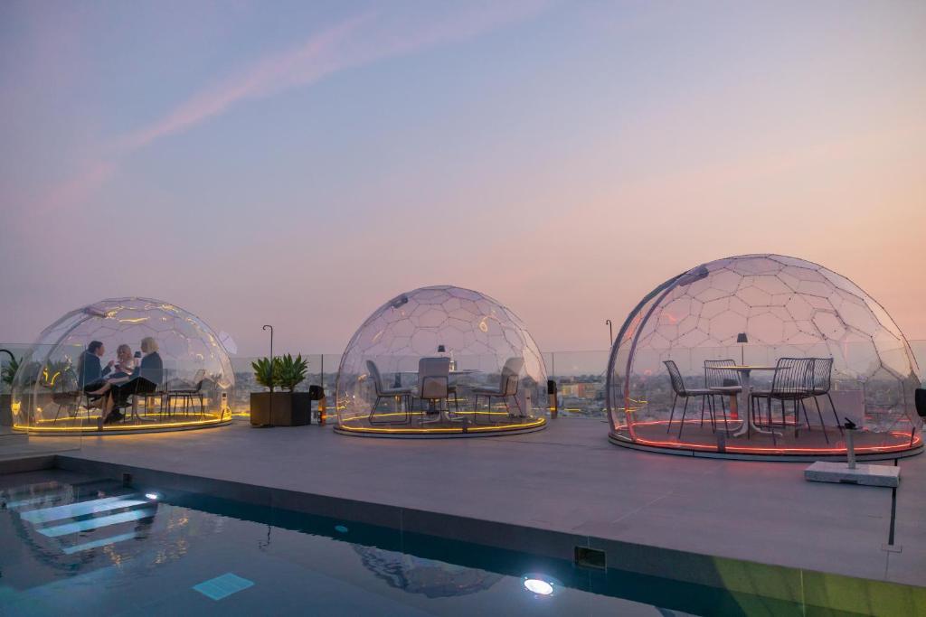 two domes with tables and chairs in them next to a pool at Neoma in Athens