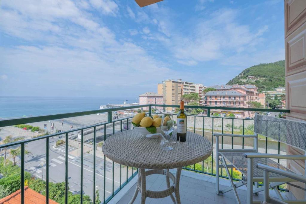 un tavolo con una bottiglia di vino e frutta sul balcone di Hotel Riviera a Deiva Marina