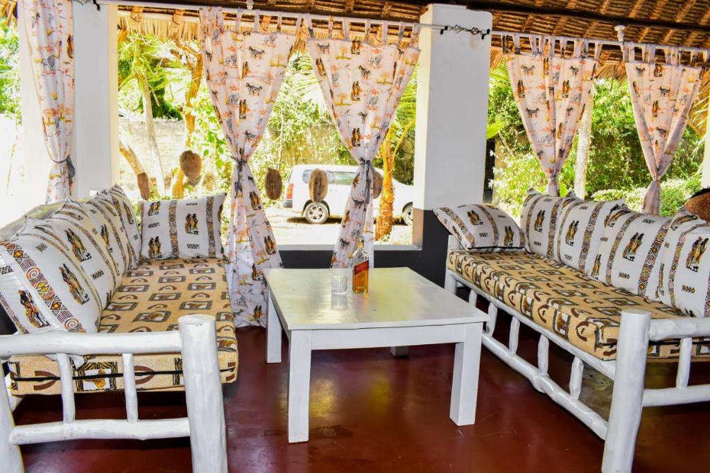 sala de estar con sillas blancas y mesa en Private room in a villa en Diani Beach