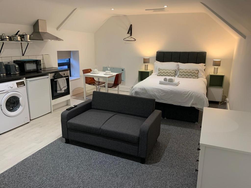 a bedroom with a bed and a chair and a kitchen at Guest Homes - Eign Street Apartments in Hereford