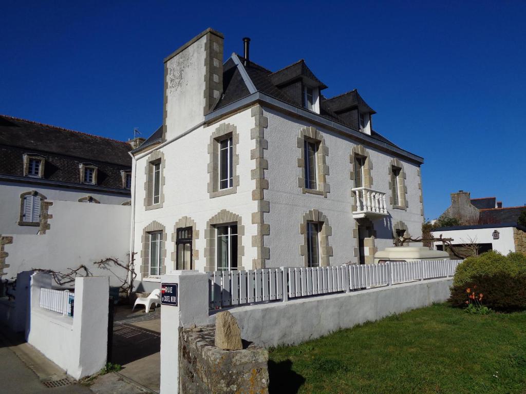 uma grande casa branca com uma cerca em frente em la maison blanche em Cléden-Cap-Sizun