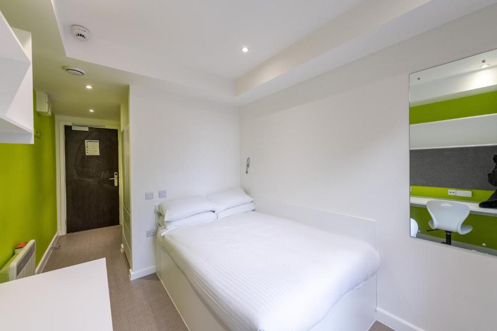 a small bedroom with a white bed and green walls at University of Bath City Accommodation in Bath