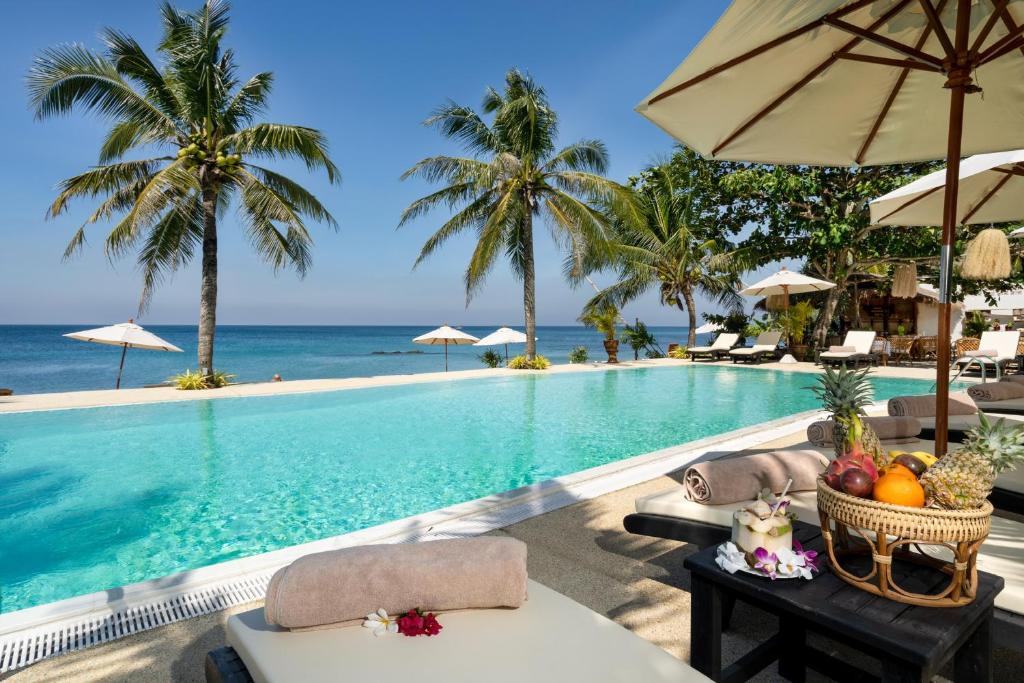 ランタ島にあるLanta Palace Beach Resort & Spa - Adult Onlyのテーブルとパラソル付きのプールを提供しています。