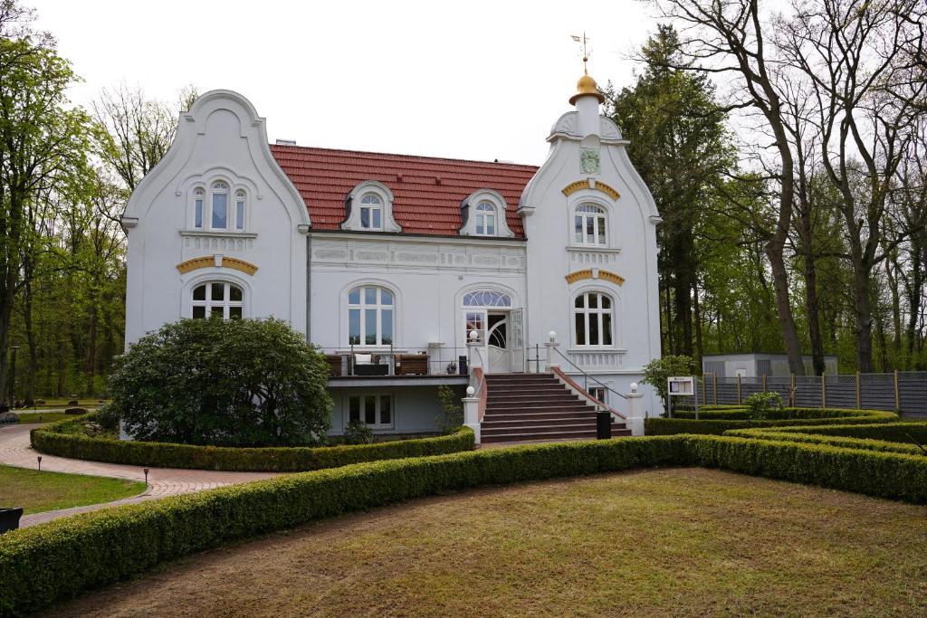 ein großes weißes Gebäude mit rotem Dach in der Unterkunft Jagdschlösschen Schwartow in Boizenburg