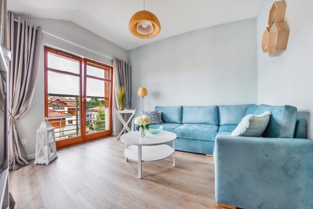 a living room with a blue couch and a table at Apartamenty Sun & Snow Neptun Park in Gdańsk