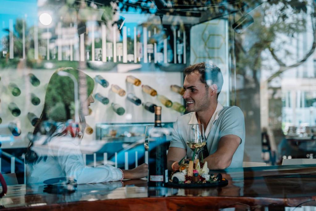 a man sitting at a table with a glass of wine at Essence Hotel Boutique in Torremolinos