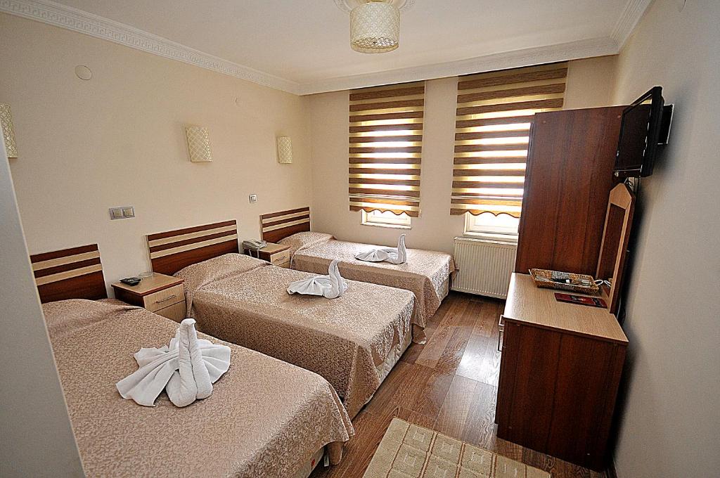 a hotel room with three beds and a television at İnci Hotel Cappadocia in Nevsehir