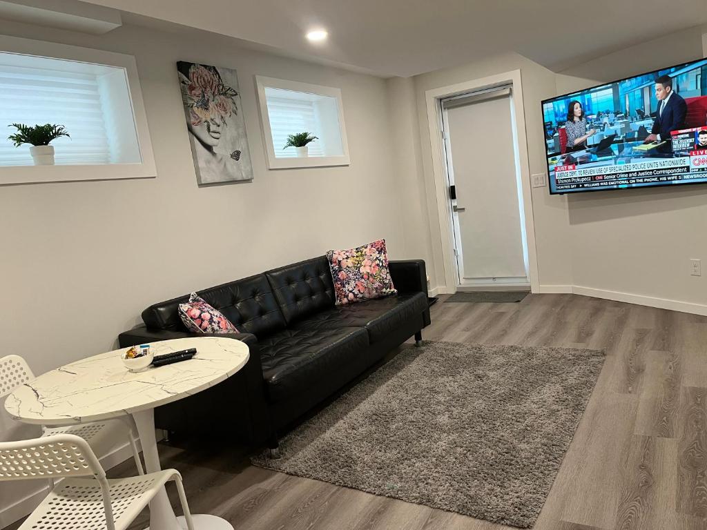 a living room with a black couch and a table at Cozy Private 1 bedroom basement suite - free parking and free Wifi in Winnipeg