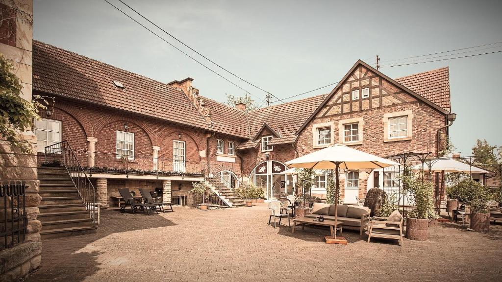 a large brick building with chairs and an umbrella at Landhotel Sonnenhof in Siebeldingen