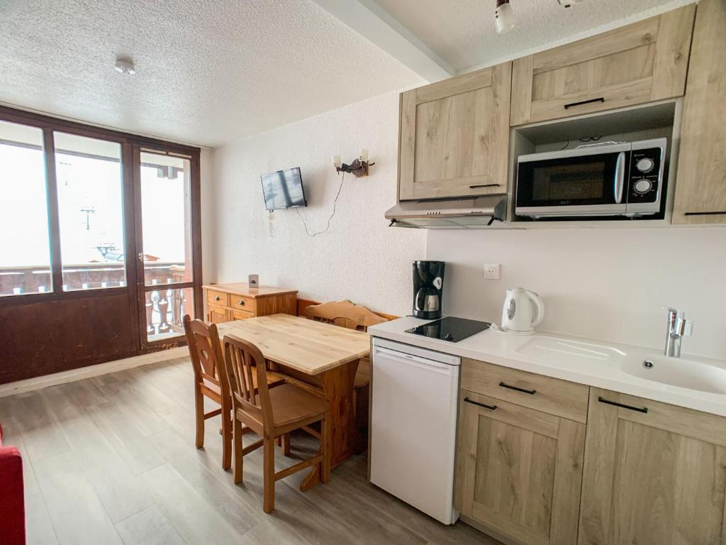 une petite cuisine avec une table et un micro-ondes dans l'établissement Studio lumineux 4 pers · Balcon · Proche remontées · Ski aux pieds · Animaux acceptés - FR-1-502-309, à Tignes