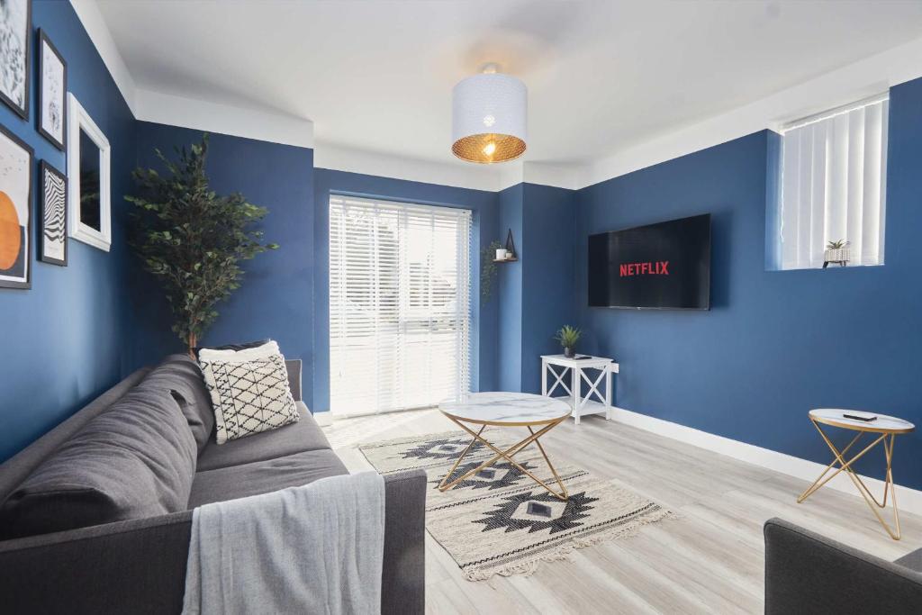 sala de estar con paredes azules y sofá en Homebird Property - Ash Tree House, en Leeds