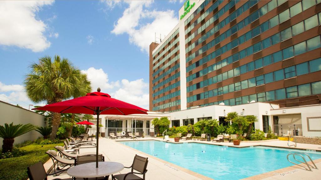 un hotel con piscina y mesa con sombrilla en Holiday Inn Houston S - NRG Area - Med Ctr, an IHG Hotel en Houston