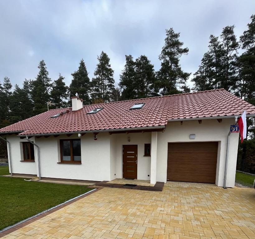 Biały dom z czerwonym dachem w obiekcie Dom Przy Lesie na Warmii w mieście Woryty