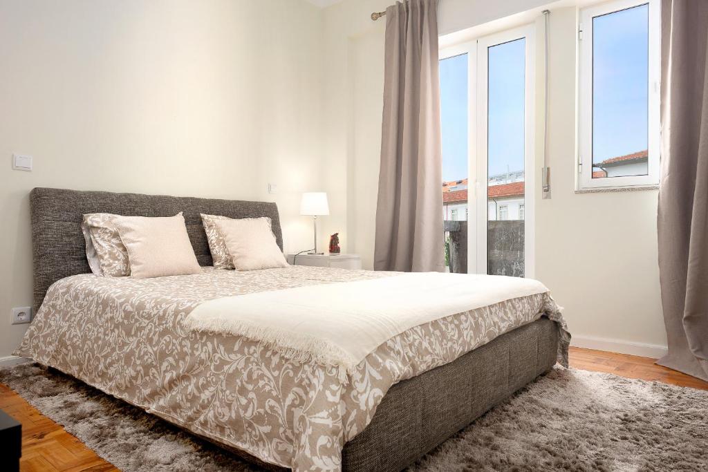 a bedroom with a bed and a large window at Sé Apartamentos - Casa Do Raio Center Apartments in Braga