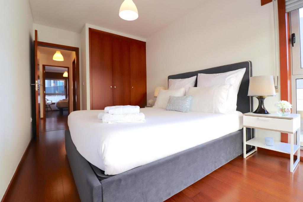 a bedroom with a large white bed with a desk at Sé Apartamentos - Cruz de Pedra Apartment in Braga