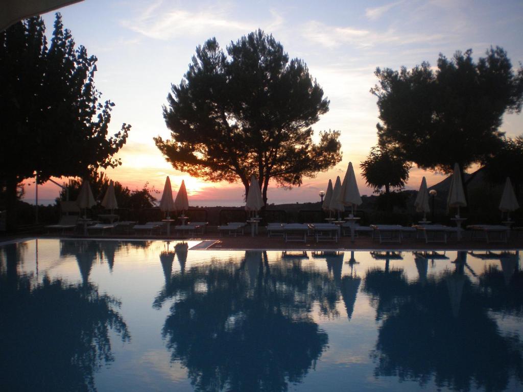 einem Pool mit Bäumen und einem Sonnenuntergang im Hintergrund in der Unterkunft Fonteluna Residence in Centola