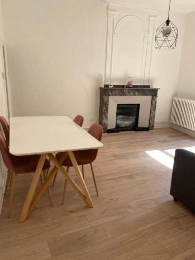 a table and chairs in a living room with a fireplace at Appartement de charme au cœur du centre ville . in Millau