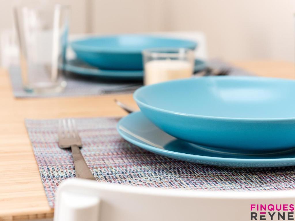 uma mesa com uma tigela azul, um prato e um garfo em Algues apt 8 em Platja d'Aro