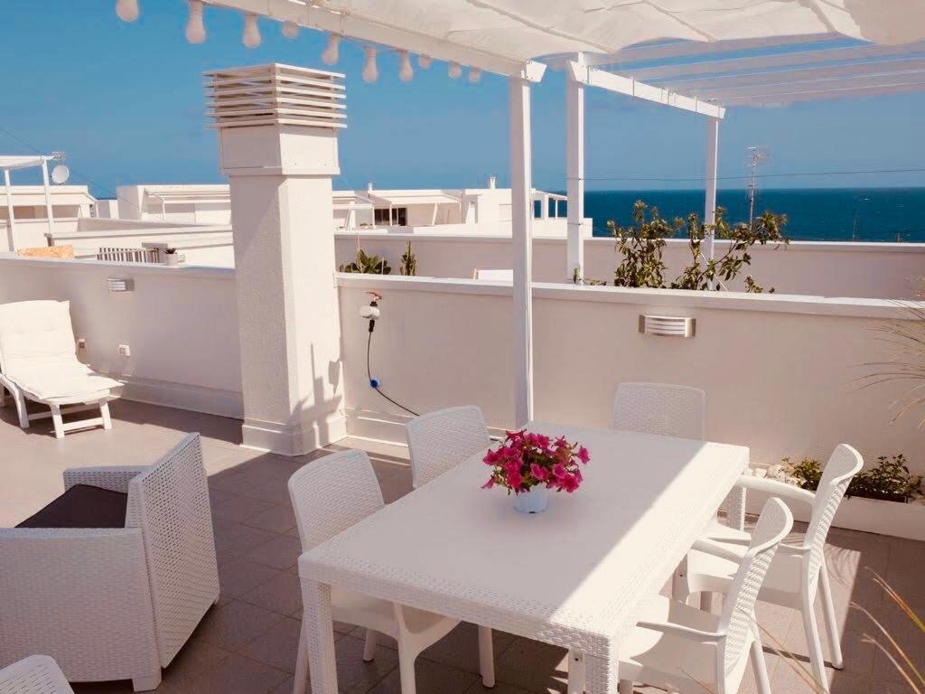 a white table and chairs on a balcony with the ocean at Dimora Punta Azzurra in Polignano a Mare