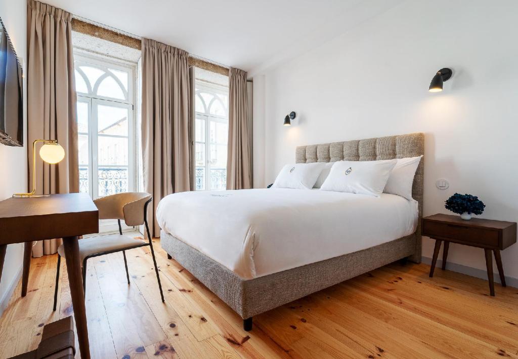 Schlafzimmer mit einem großen weißen Bett und einem Schreibtisch in der Unterkunft LP Heritage Apartments in Braga