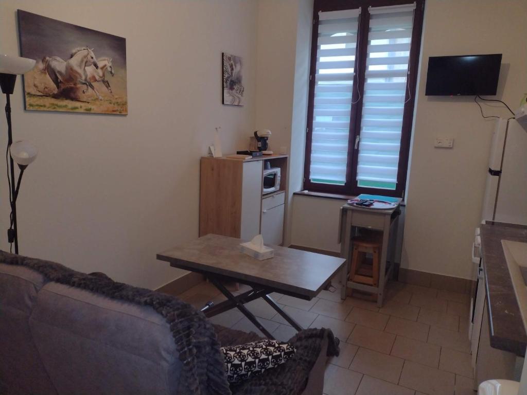 sala de estar con mesa y cocina pequeña en Appartement RDC chez Caroline en Bourbonne-les-Bains