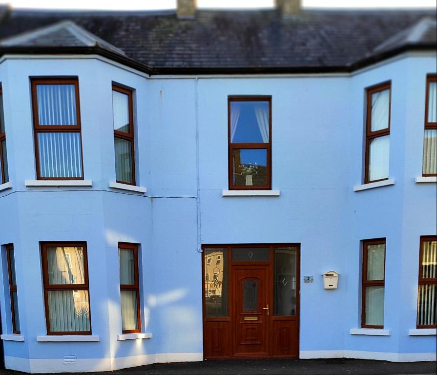 a white house with a red door and windows at Luxury 3 bedroom house with peaceful garden, sleeps 6 and 2 mins to beach in Bundoran
