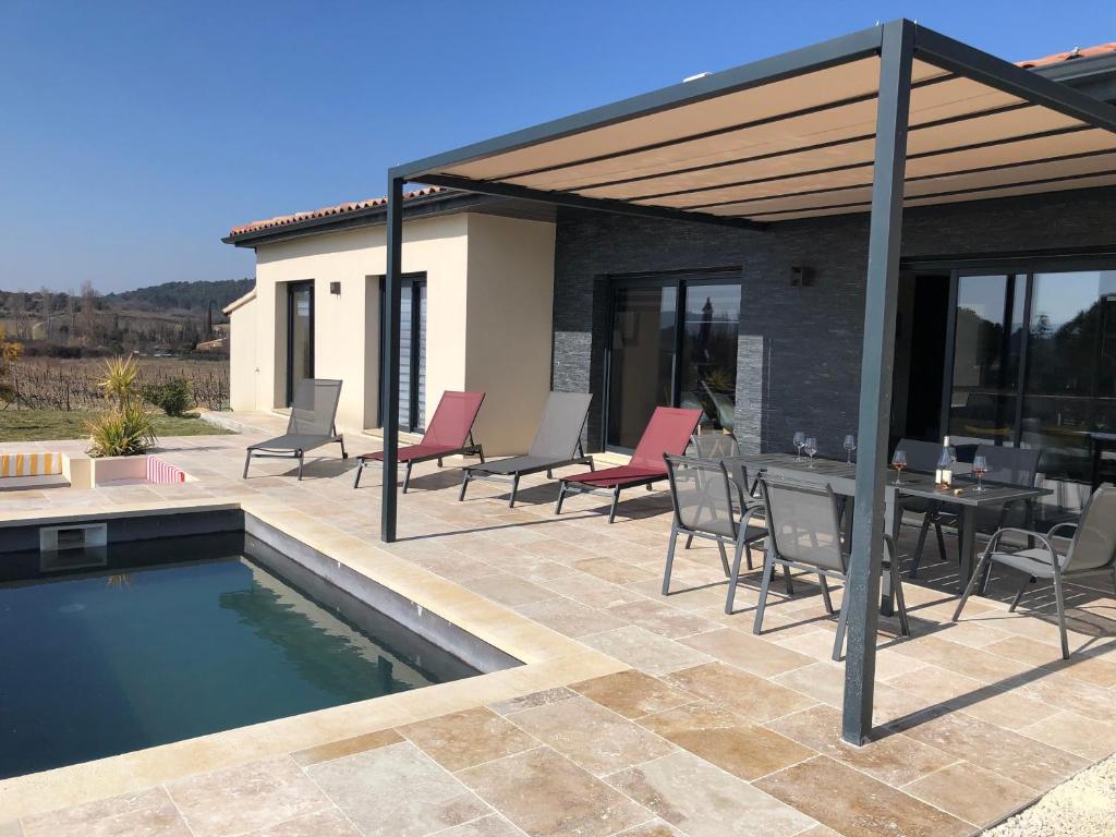 un patio avec une table et des chaises à côté d'une piscine dans l'établissement La Petite Reine, à Villes-sur-Auzon